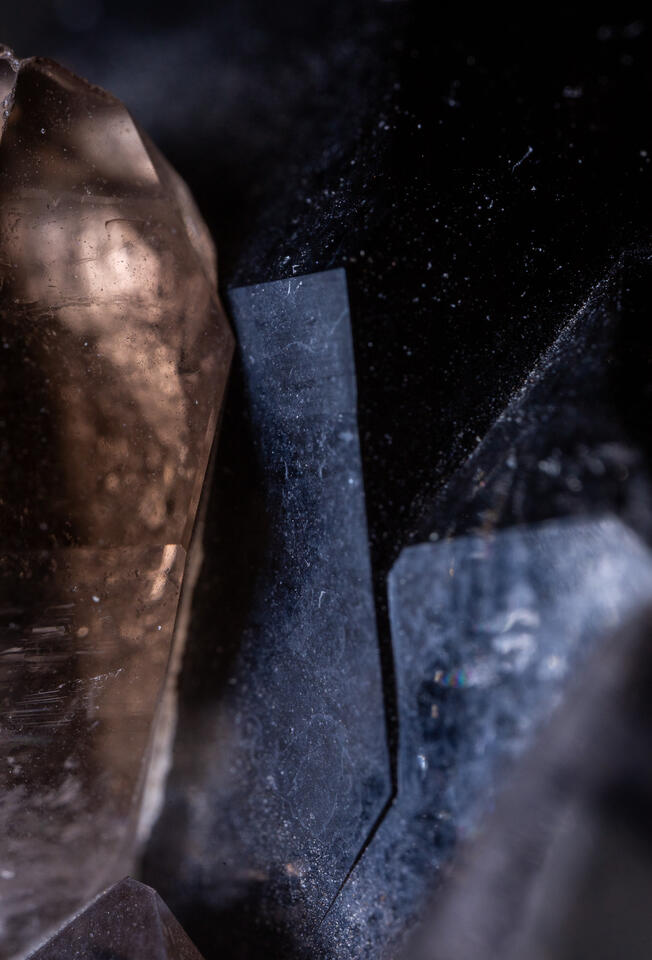 Close-up of black smoky quartz crystal with sharp intersecting planes and smooth reflective surfaces.