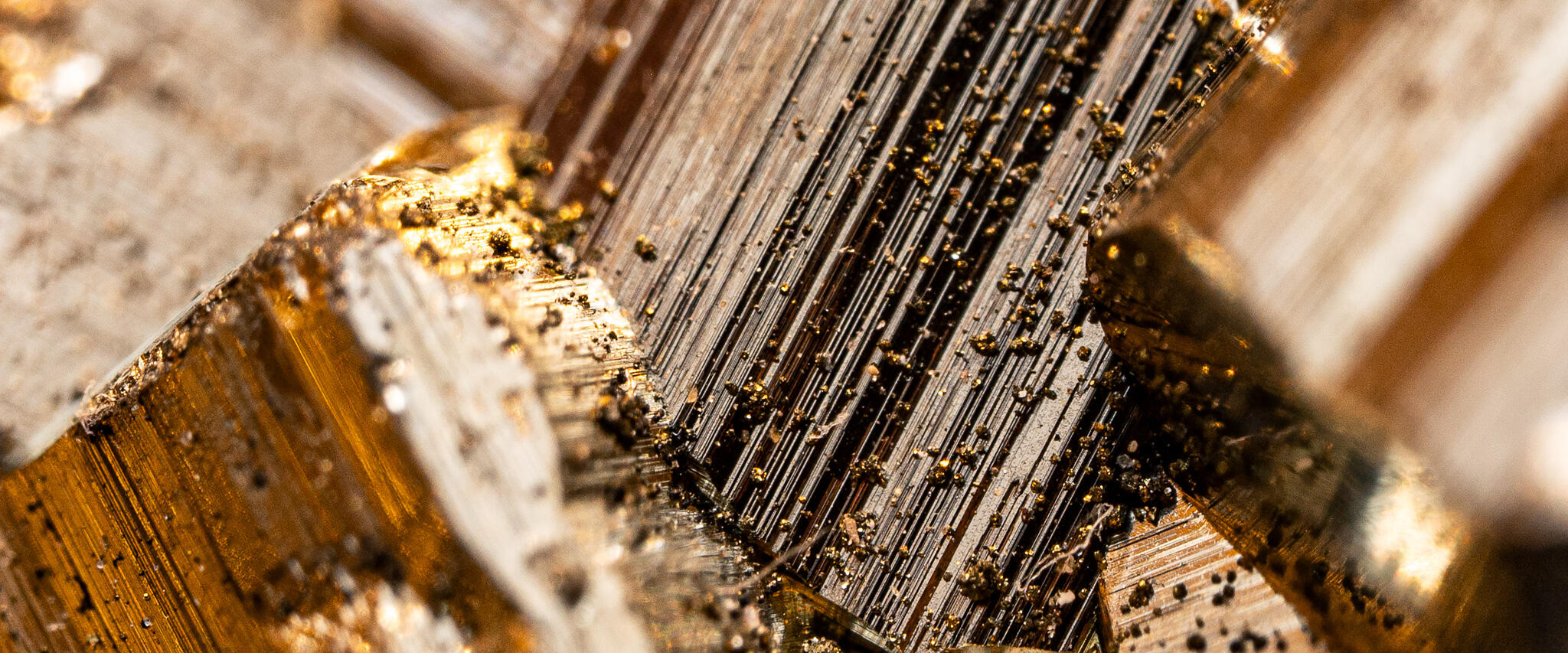 Macro view of golden pyrite crystals showing dense layered striations and metallic luster.