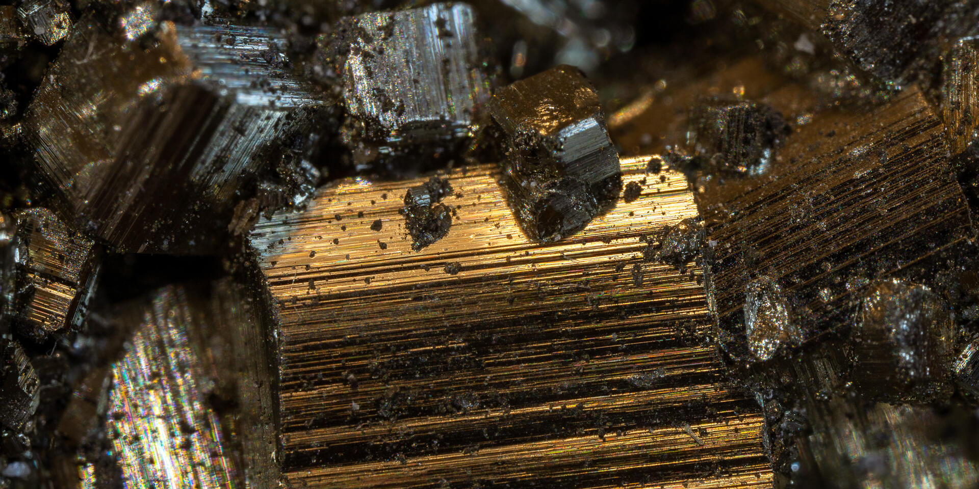 Close-up of pyrite cubes in metallic gold and gray tones with sharp edges.