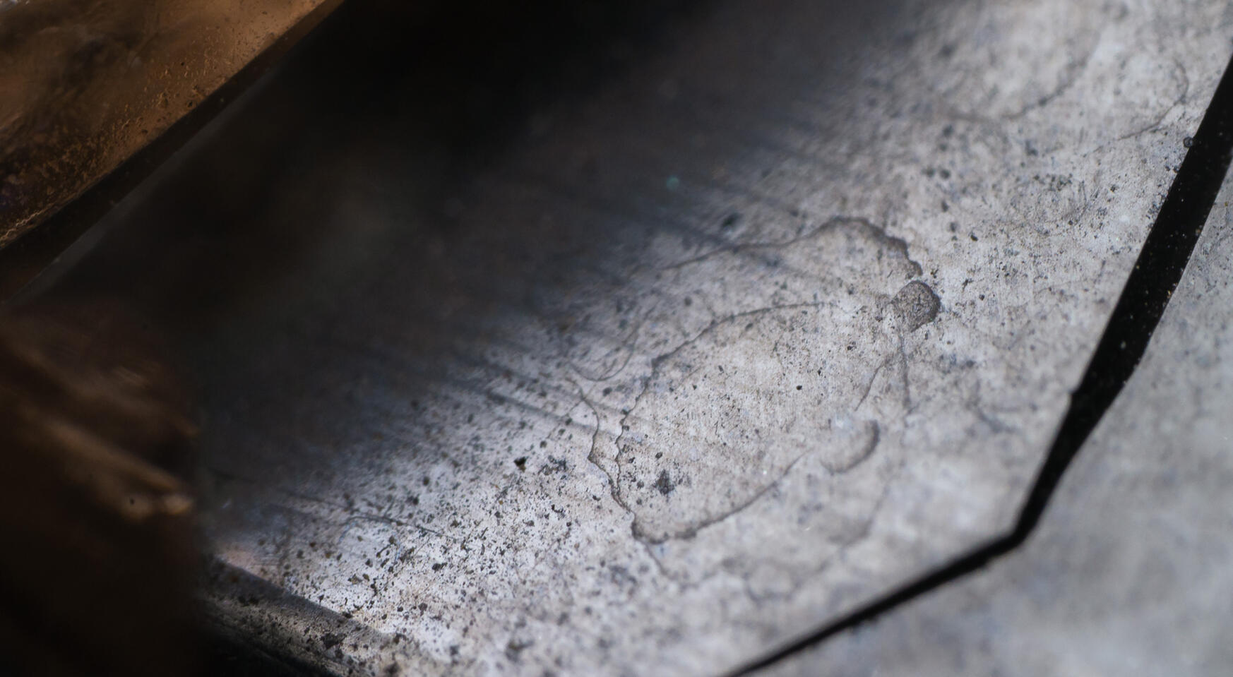 Macro of a silver-gray quartz crystal face showing etched patterns and a fine granular texture.